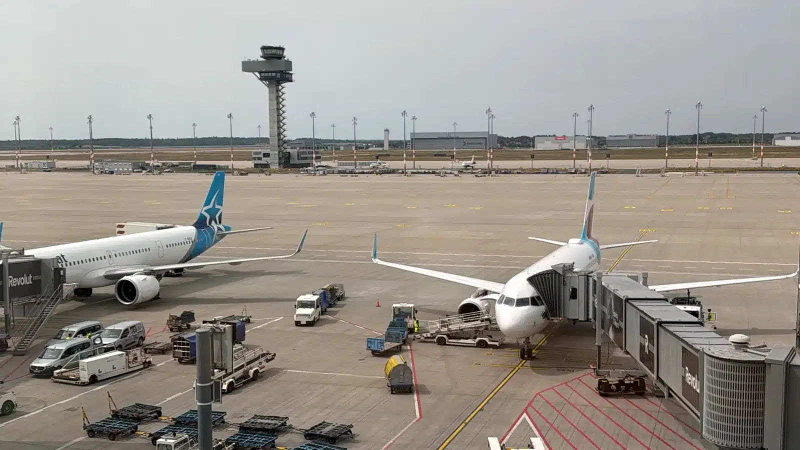 Air Transat Airbus A321 und Eurowings Airbus A320 am Gate des Flughafens BER, im Hintergrund der Tower