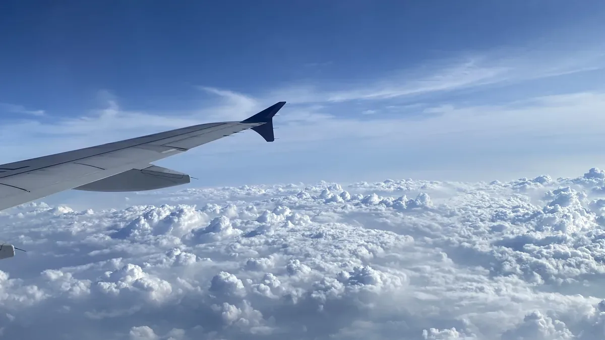 Flugzeugflügel über einer dichten Wolkendecke bei blauem Himmel