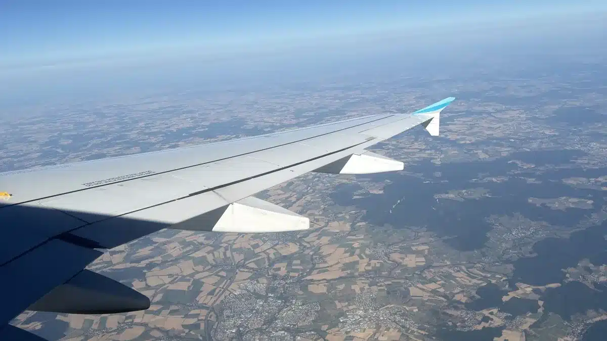 Flugzeugflügel mit ausgefahrenen Landeklappen über Deutschland