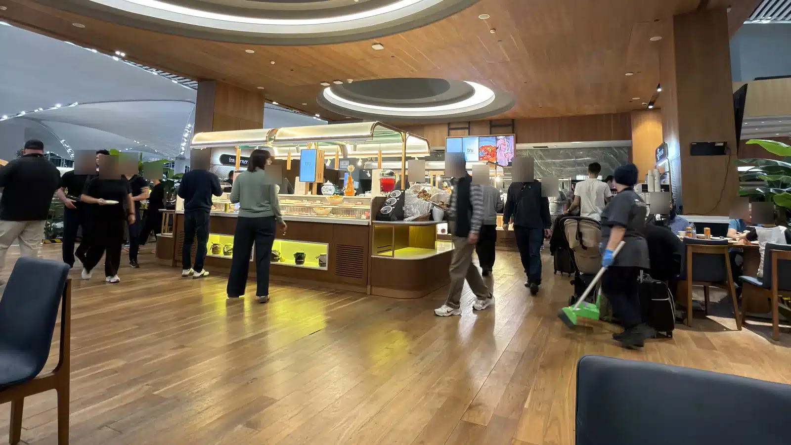 Buffetbereich der iGA Lounge am Flughafen Istanbul mit Holzdecke und Gästen