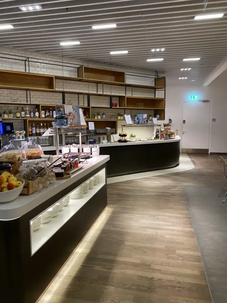 Buffettheke und Selbstbedienungsbar mit Spirituosen in der Lufthansa Business Lounge am BER