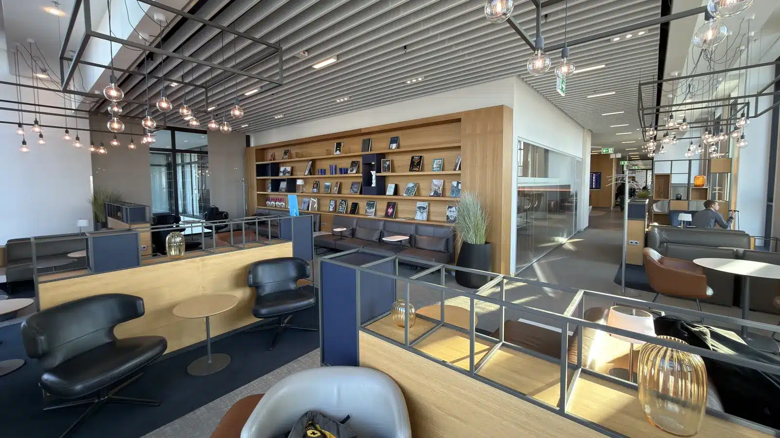 Sitzbereich der Lufthansa Business Lounge am Flughafen BER mit Ledersesseln und Bücherwand