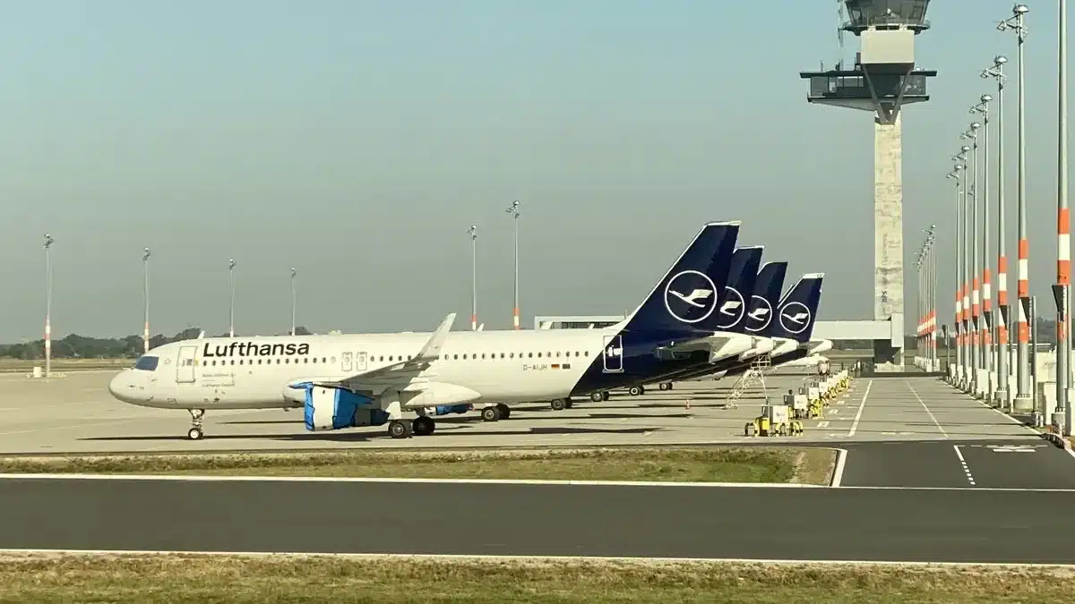 Mehrere geparkte Lufthansa Flugzeuge vor dem Tower am Flughafen BER