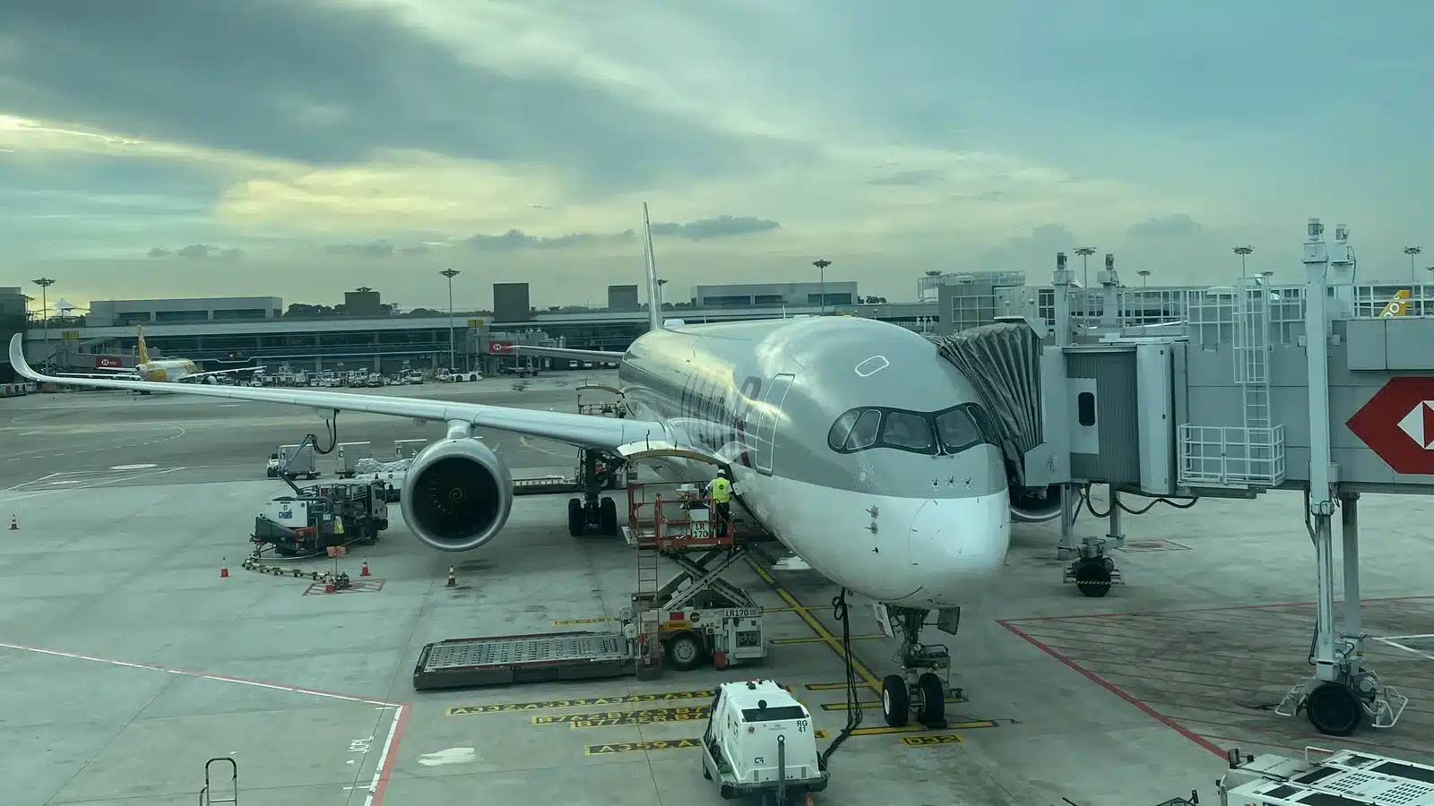 Airbus A350 von Qatar Airways am Gate mit Fluggastbrücke und Bodenfahrzeugen