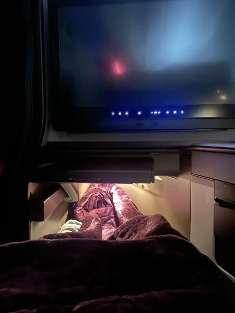 Flaches Bett in der Qatar Airways QSuite mit dicker Decke