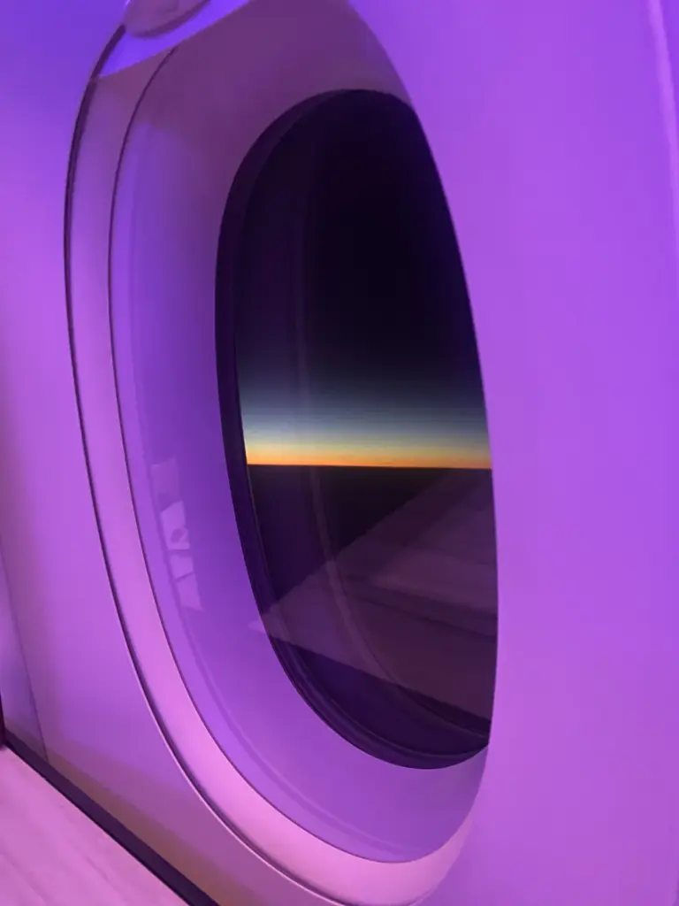 Sonnenaufgang durch das Fenster der QSuite mit violetter Kabinenbeleuchtung