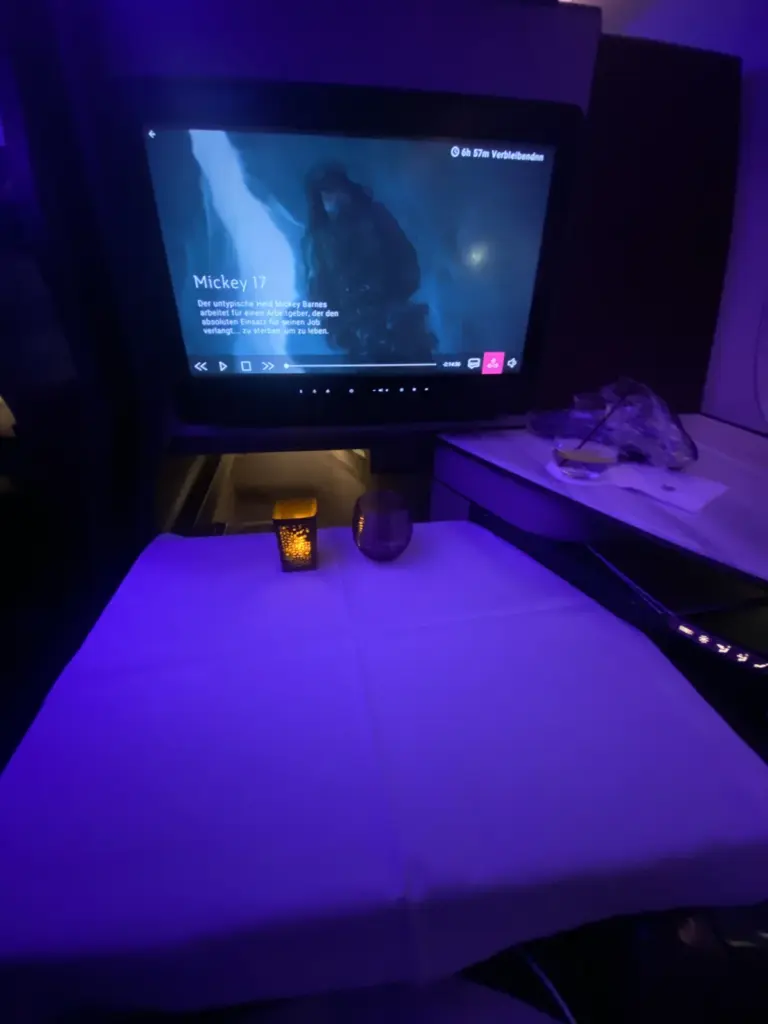 Gedeckter Tisch mit Tischdecke und Kerze in der QSuite, im Hintergrund läuft ein Film