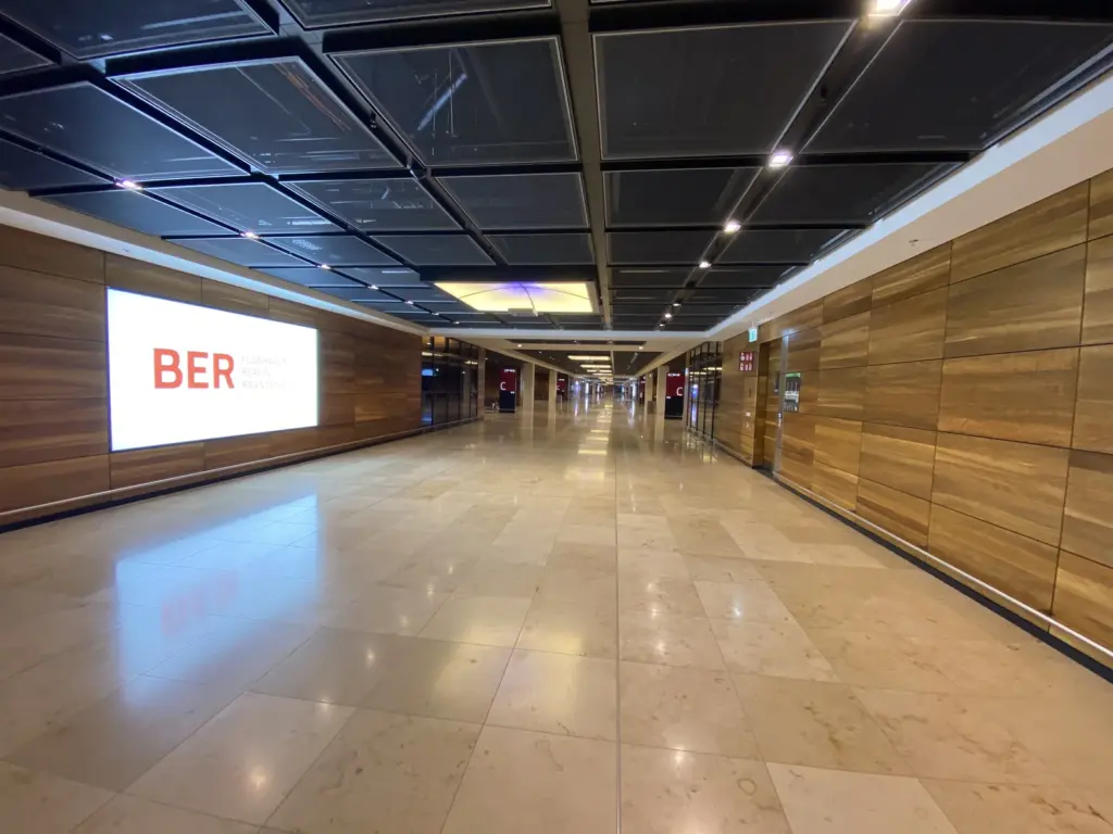 Leerer Gang im Pier des Terminal 1 am BER mit Holzwänden und BER Leuchtschild