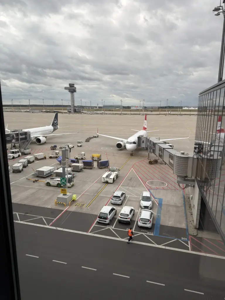 Blick aus dem Terminal auf das Vorfeld des BER mit Tower, Lufthansa und Austrian Flugzeugen am Gate